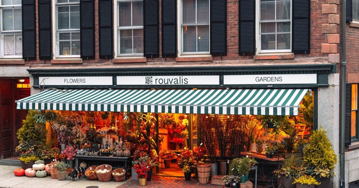 A vibrant flower shop adorned with autumn decor on a Boston street, capturing the fall essence.
