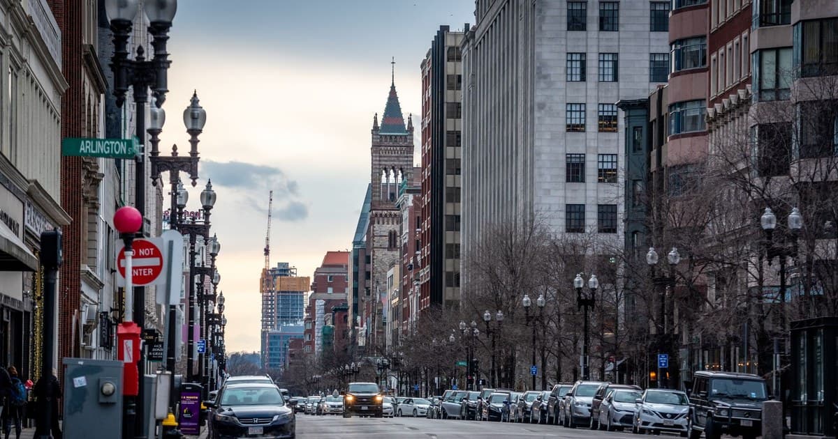 A busy street view in downtown Boston, Massachusetts during dusk showcasing urban architecture and traffic flow.