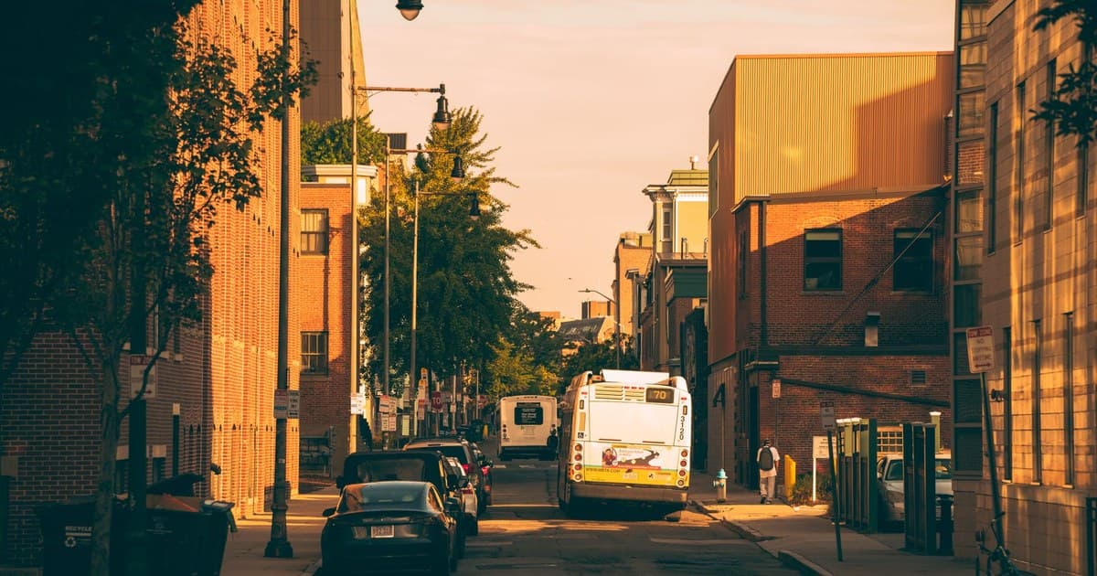 Vibrant city street view with a bus and cars under warm sunset lighting in Boston.